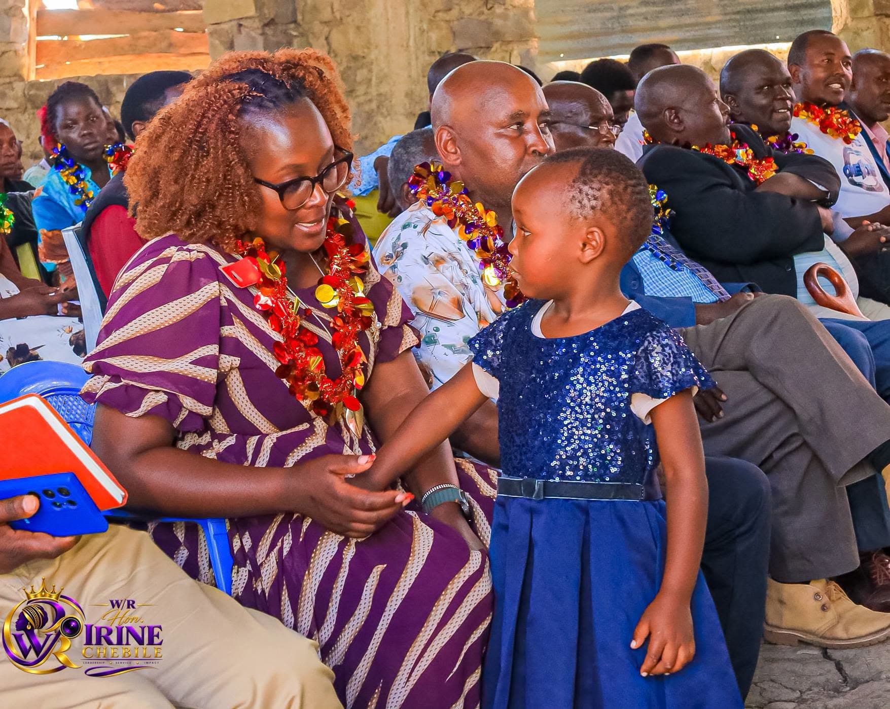Irine Chebile holding the hands of a young girl at a community gathering